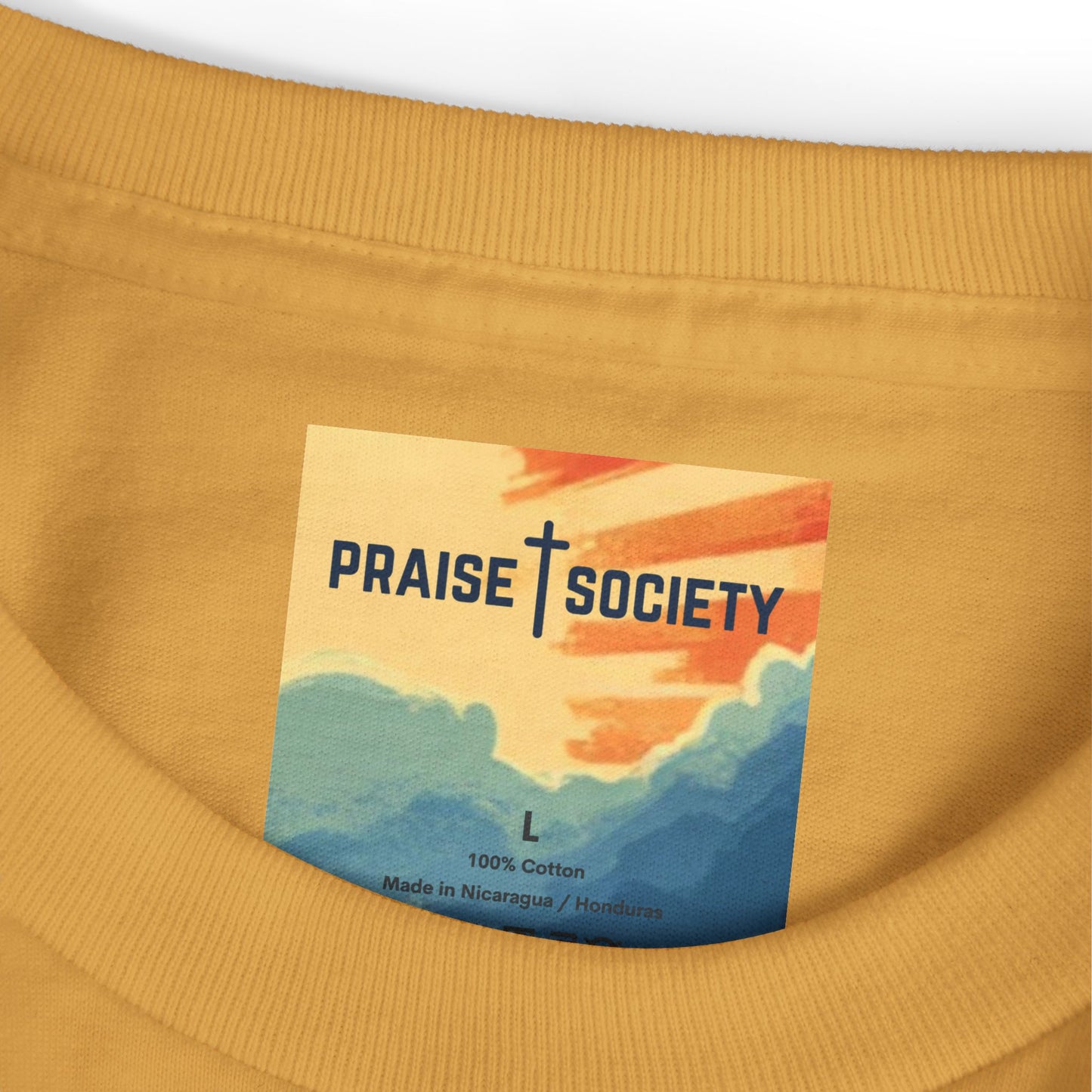 Close-up of a mustard yellow garment with a 'Praise Society' label featuring a colorful design.
