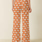 Person wearing orange and white patterned pants on a plain background