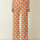 Person wearing orange and white patterned pants on a beige background