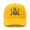 A yellow bitcoin trucker-style baseball cap featuring an embroidered Gadsden flag design with a coiled snake, stars, and the text 'DON'T TREAD ON ME' on the front panel.