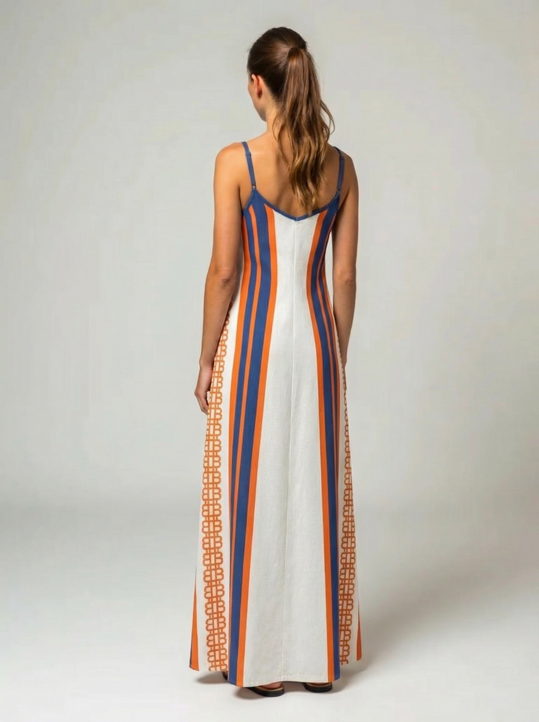 Woman wearing a long Bitcoin maxi dress with blue and orange stripes on a white background