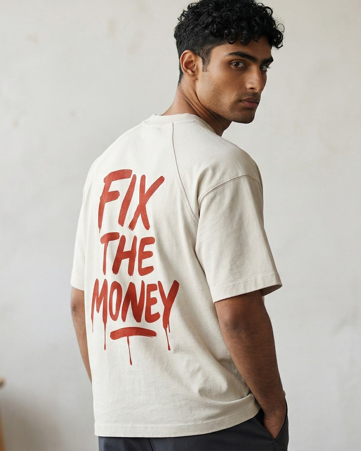 Man wearing a white t-shirt with 'FIX THE MONEY' text in red indoors. SVRN Society