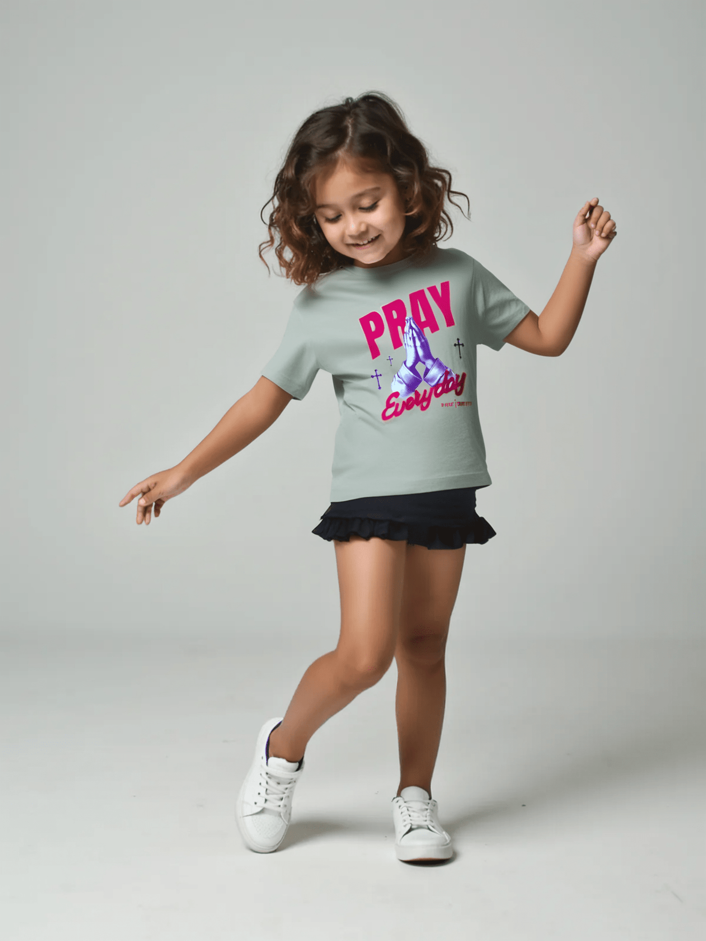 Child wearing a grey t-shirt with 'PRAY Everyday' text on a gray background