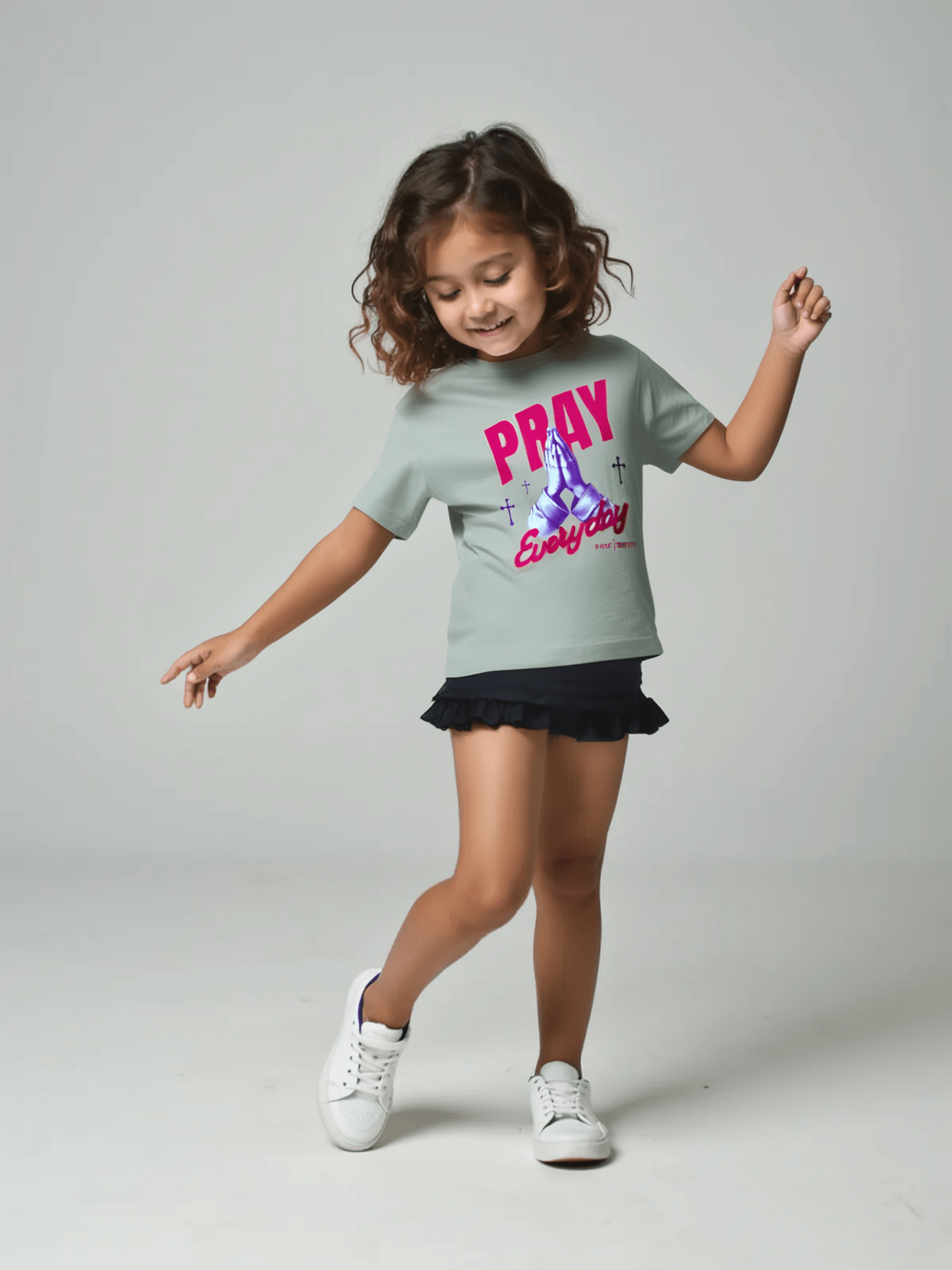 Child wearing a grey t-shirt with 'PRAY Everyday' text on a gray background