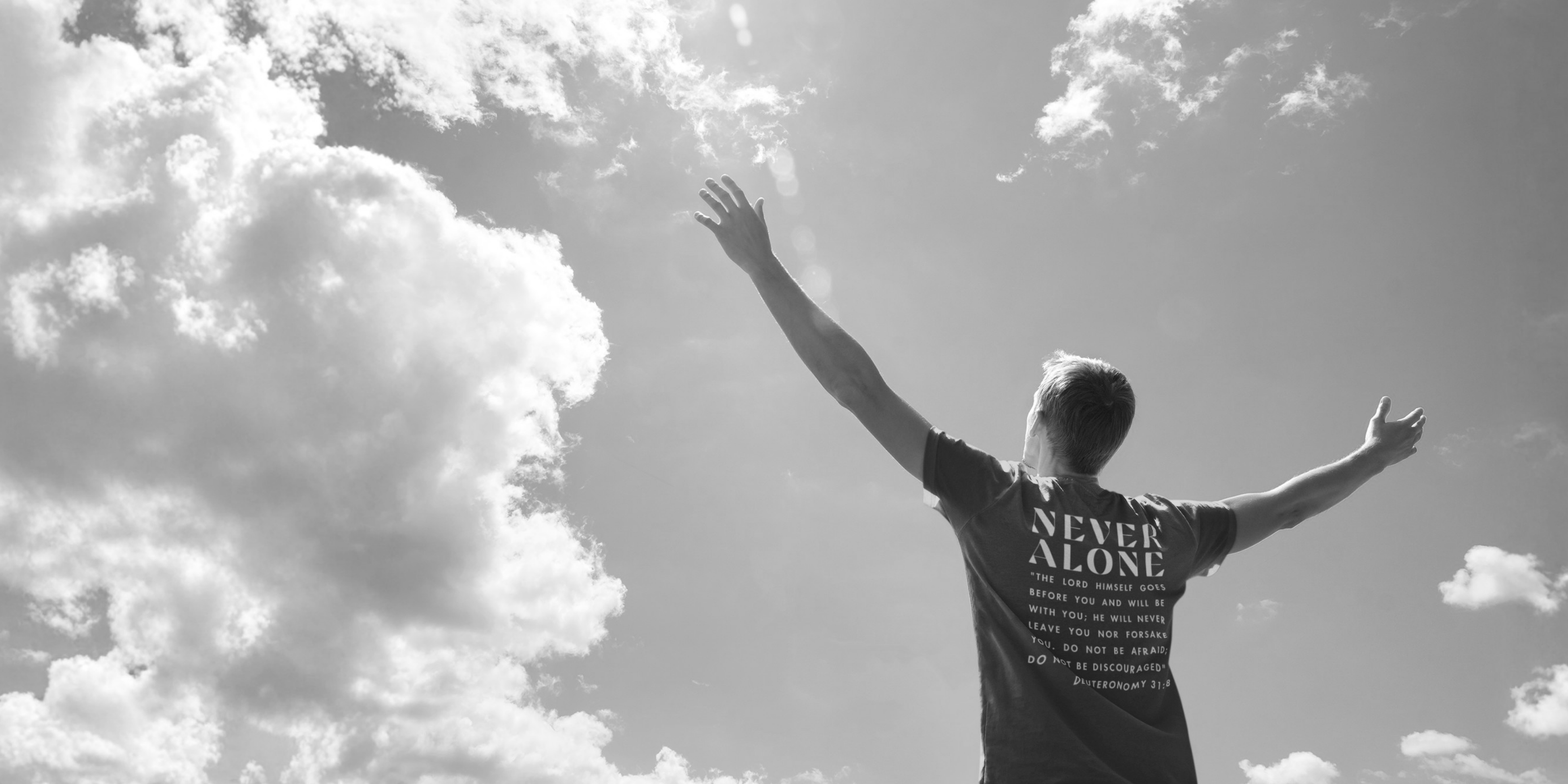 Person with 'Never Alone' shirt against a cloudy sky
