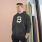Man wearing a (Charcoal Grey) hoodie with a Bitcoin logo against a beige wall.