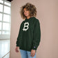 Person wearing a (Dark Green) hoodie with a Bitcoin logo against a beige wall.