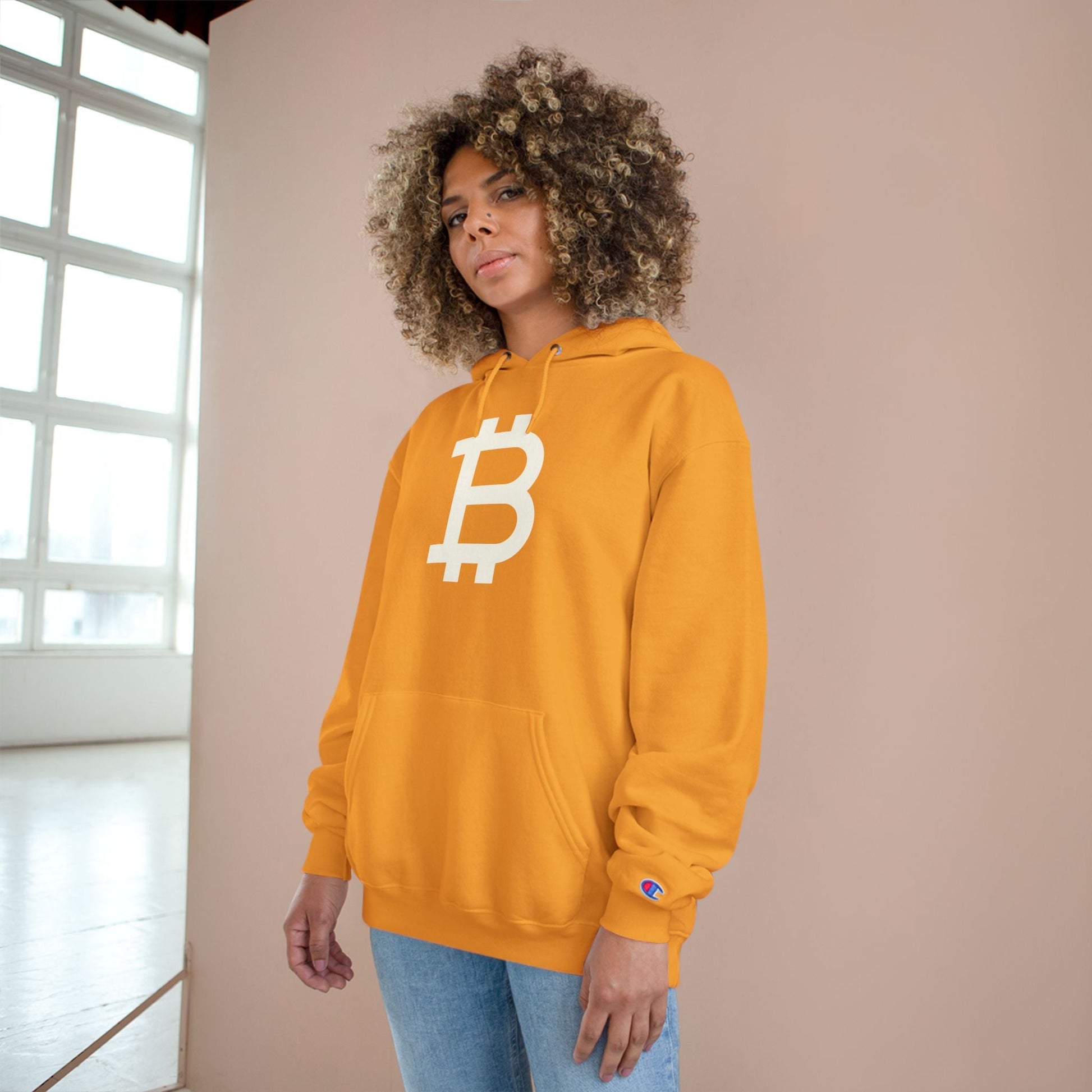 Person wearing a (Gold) hoodie with a Bitcoin logo against a neutral background