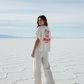 woman wearing a white bitcoin t-shirt with 'FIX THE MONEY' text in a desert landscape