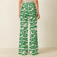 Person wearing white bitcoin pants with green parisain text pattern on a neutral background 