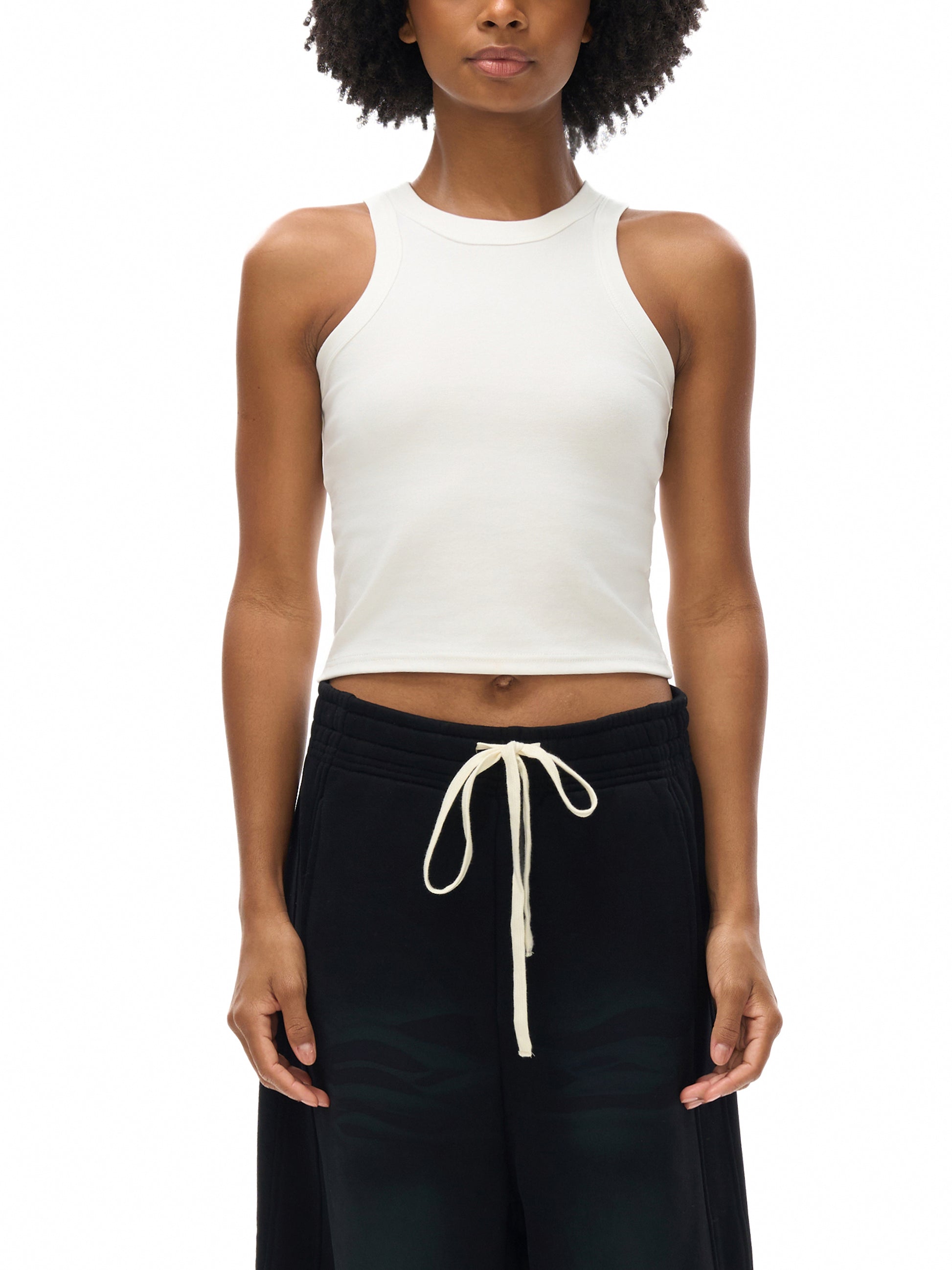 Woman wearing a white bitcoin sleeveless top and black pants with a drawstring on a white background