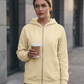 Model holding coffee in the apricot zip-up fleece hoodie, showing its plain front and split pockets.