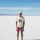 Person standing on a salt flat wearing a Satoshi Nakamoto cap and t-shirt with a star design.