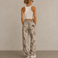 Woman in white tank top wearing Kayfabe tree camo fleece sweatpants, back view