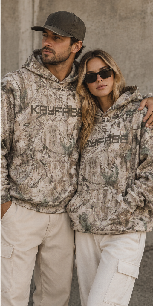 Man and woman both wearing the Kayfabe tree camo oversized fleece hoodie