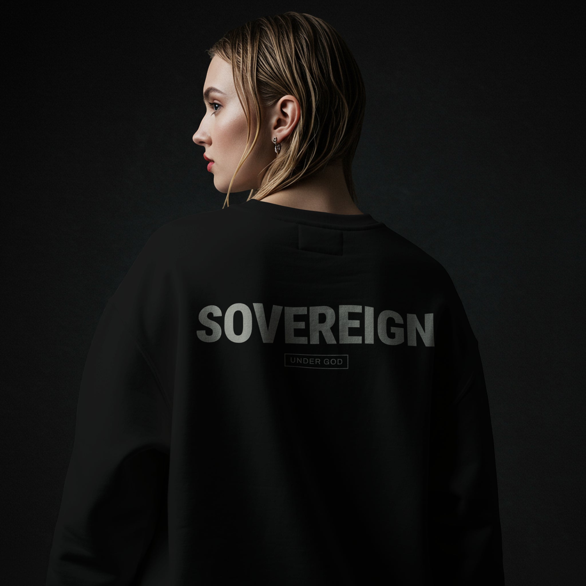 Woman wearing a black Christian sweatshirt with 'SOVEREIGN' printed on the back against a dark background