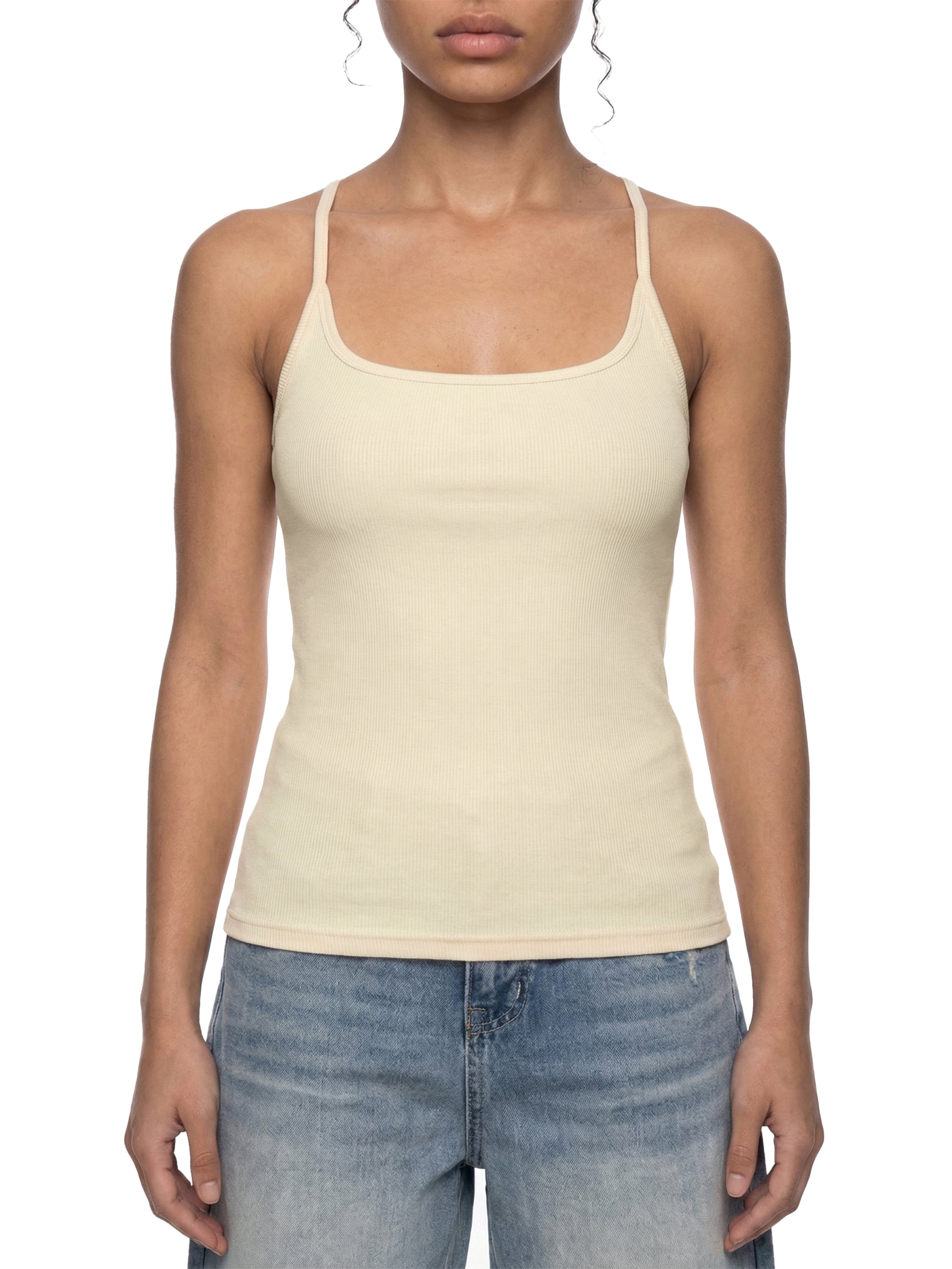 Woman wearing a beige tank top and blue jeans on a white background